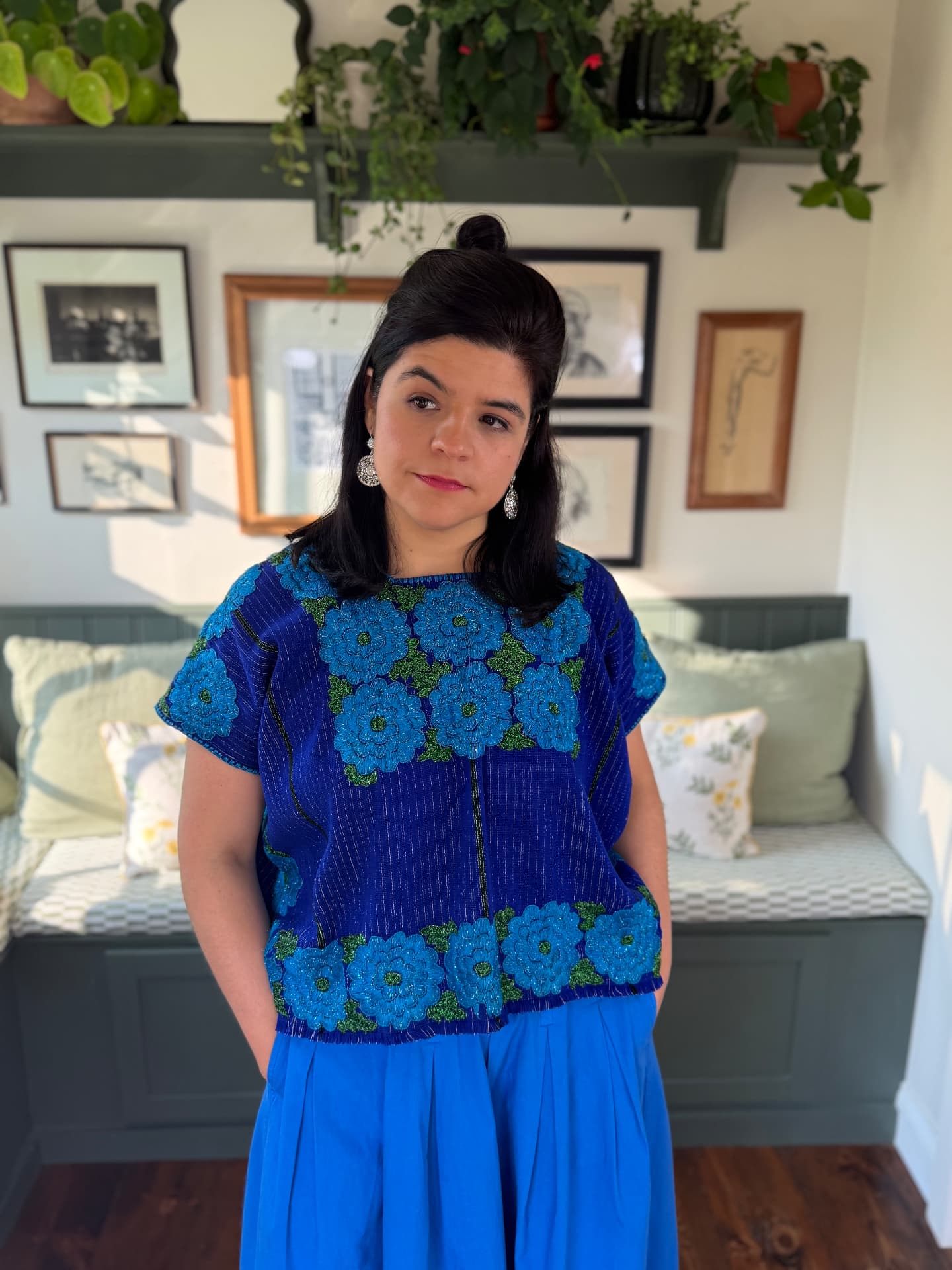 Woman wearing a cobalt blue huipil with turquoise floral embroidery