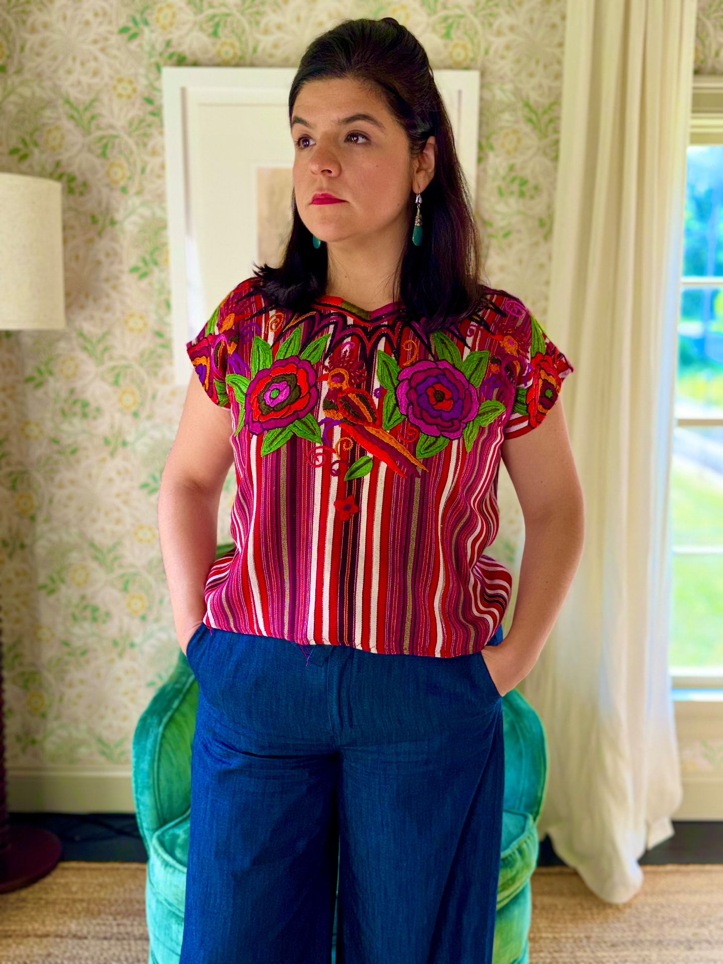 Woman wearing a striped huipil with magenta and green floral embroidery