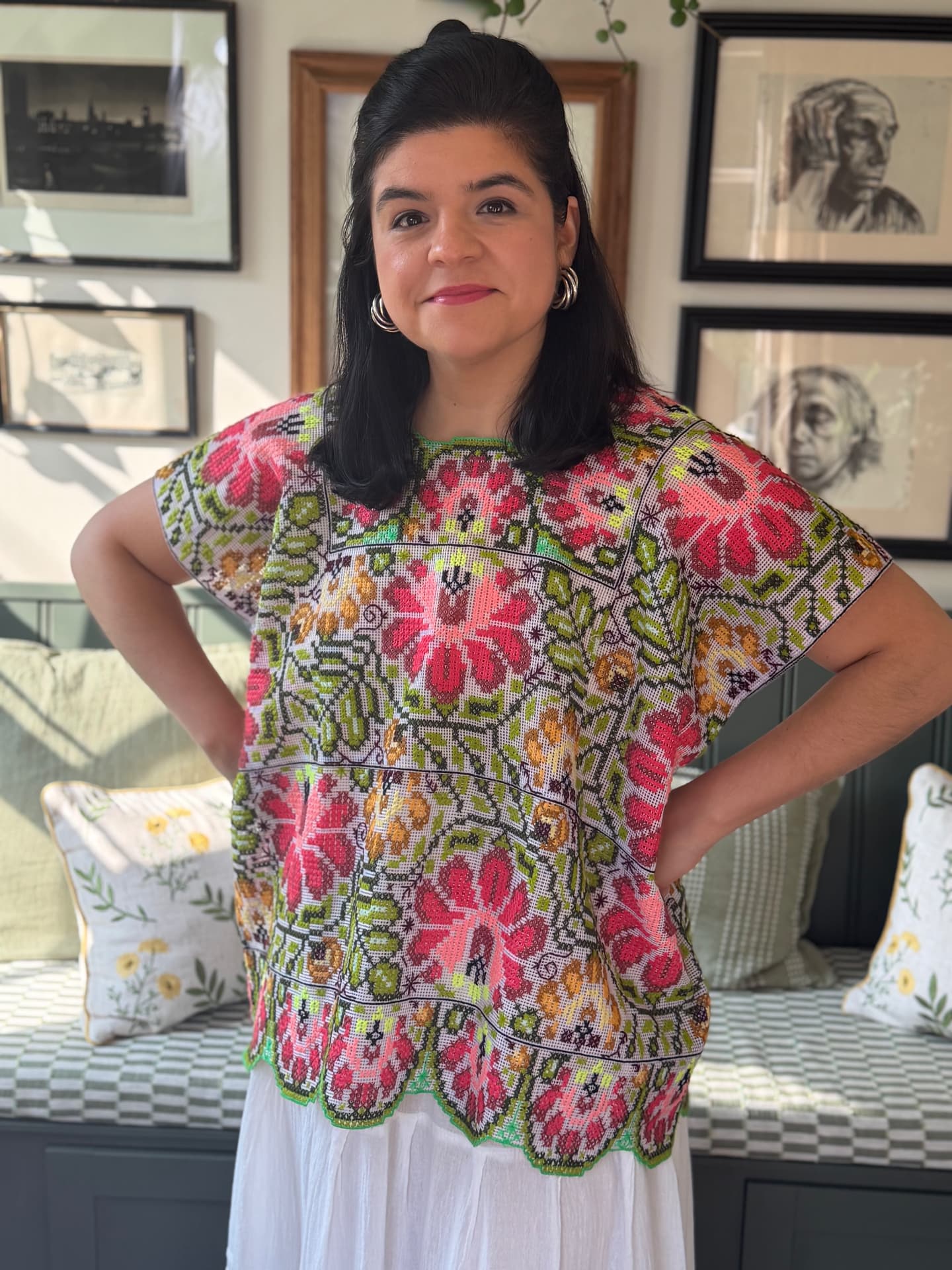 Woman wearing a cross-stitched huipil with coral and olive floral motifs